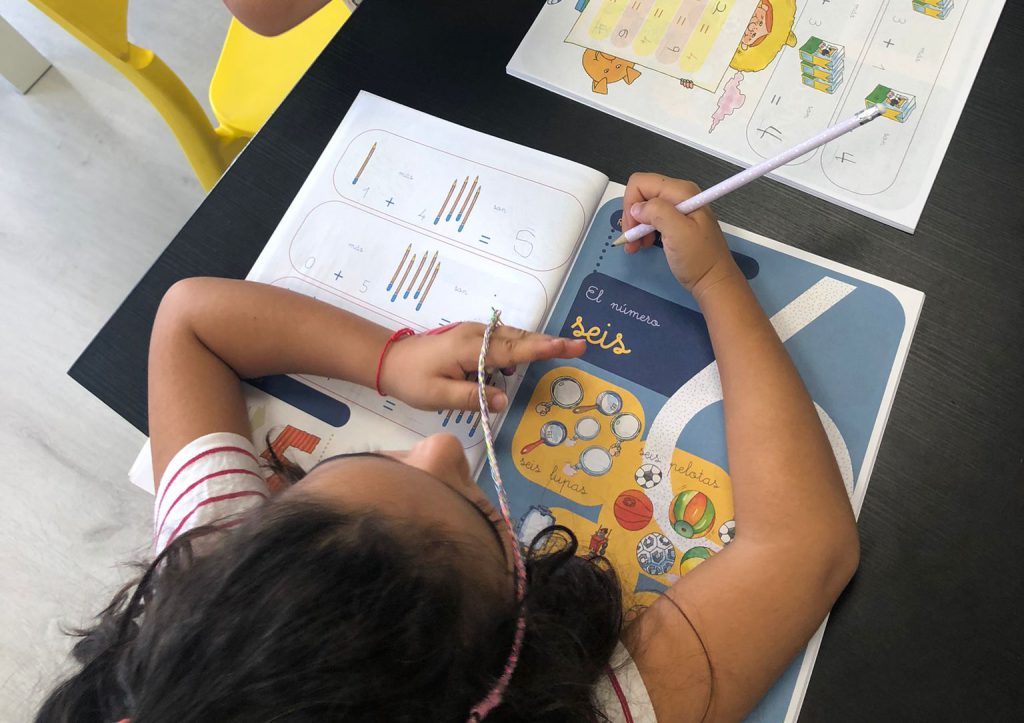 Niña realizando actividades de matemáticas con cuadernillo