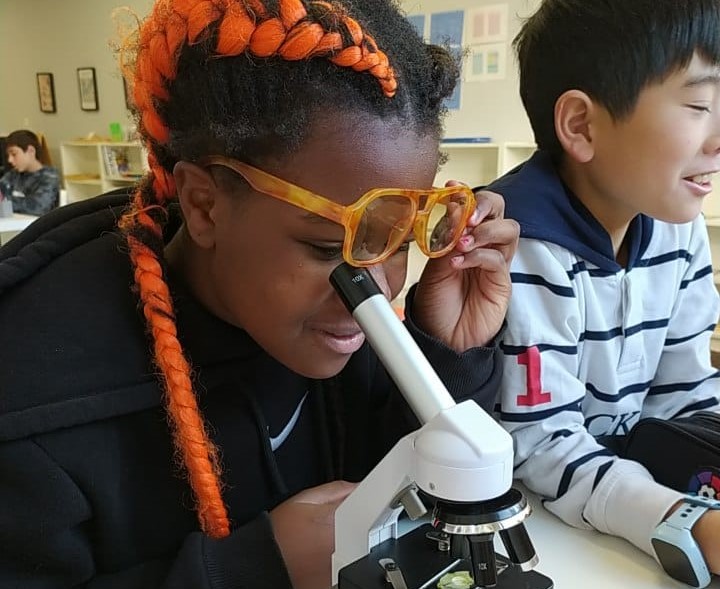 Fotografía de niña mirando por un microscopio